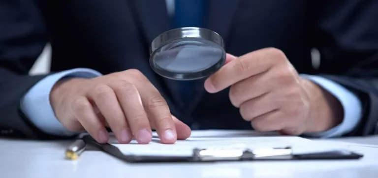 Global Surveys employee checking authenticity of a document with magnifying glass