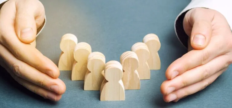 hands holding wooden figures of people