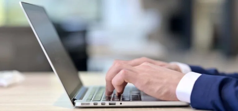 suited man typing on laptop